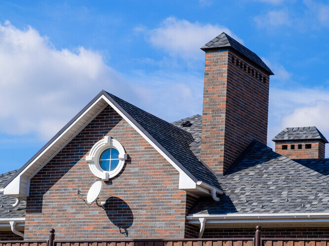 Asphalt shingle. Decorative bitumen shingles on the roof of a brick house